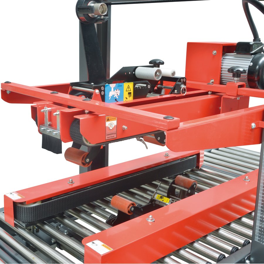 Die Förderbänder schieben den Karton durch die Führung und der Karton wird unten und oben verklebt Die Förderbänder schieben den Karton durch die Führung und der Karton wird unten und oben verklebt