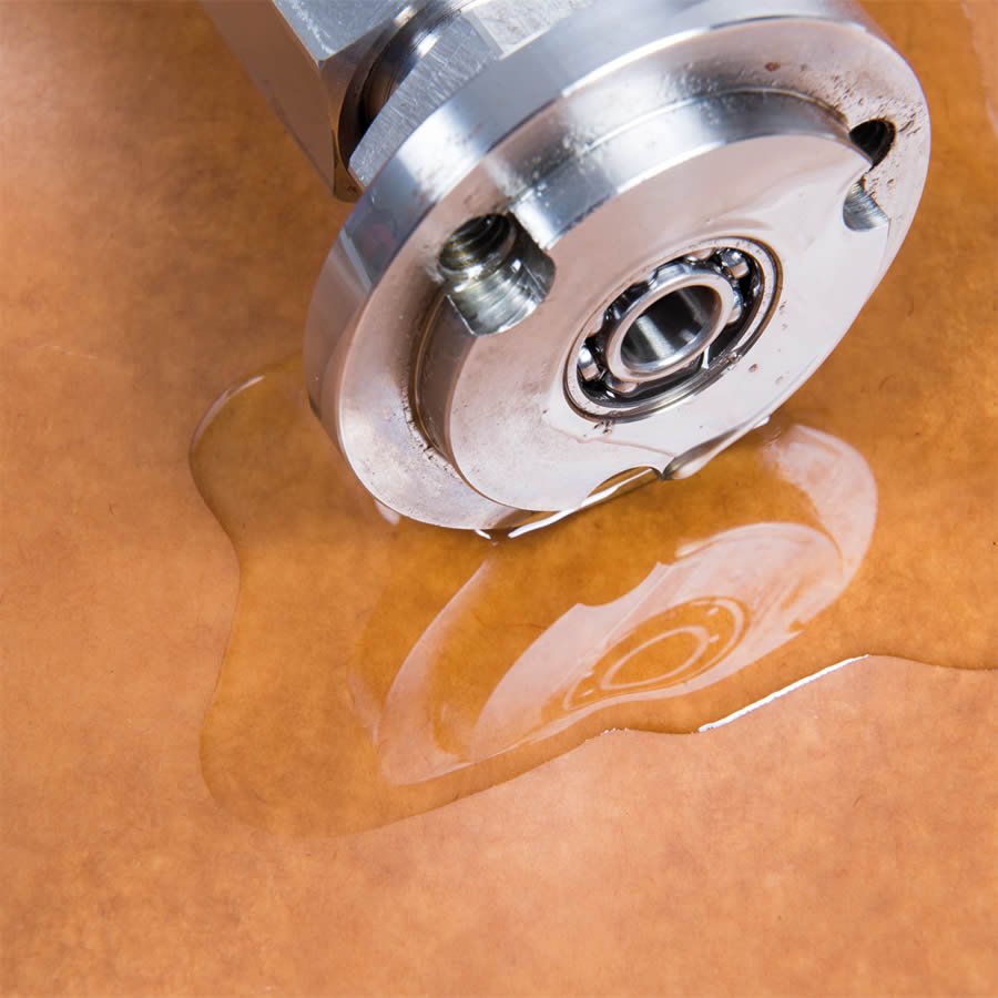 Schützt Metallteile vor Korrosion und Verschmutzung Metallteil auf Ölpapier mit Wasserpfütze